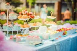 Mesa de banquete al aire libre con pasteles, fruta y dulces en varias bandejas